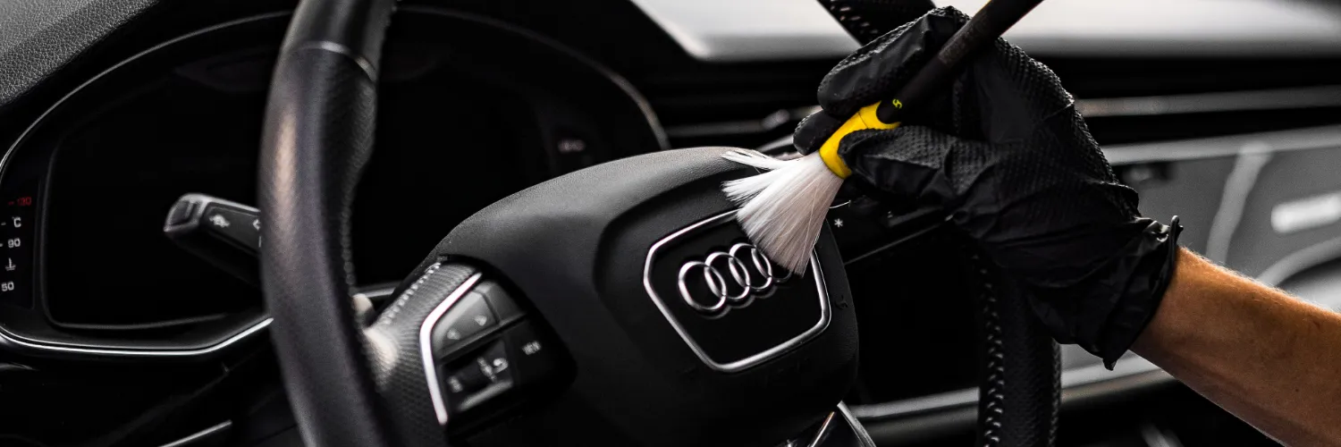 Proces czyszczenia kierownicy we wnętrzu samochodu.